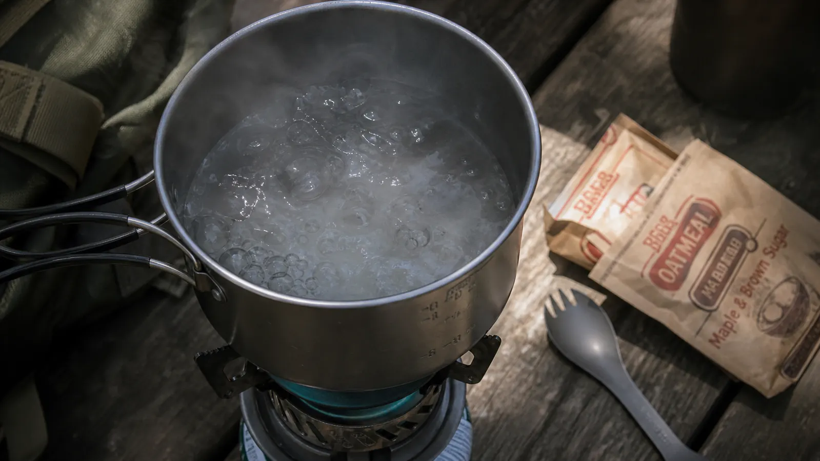 Compact camp stove packed inside a daypack next to camping gear on a truck tailgate