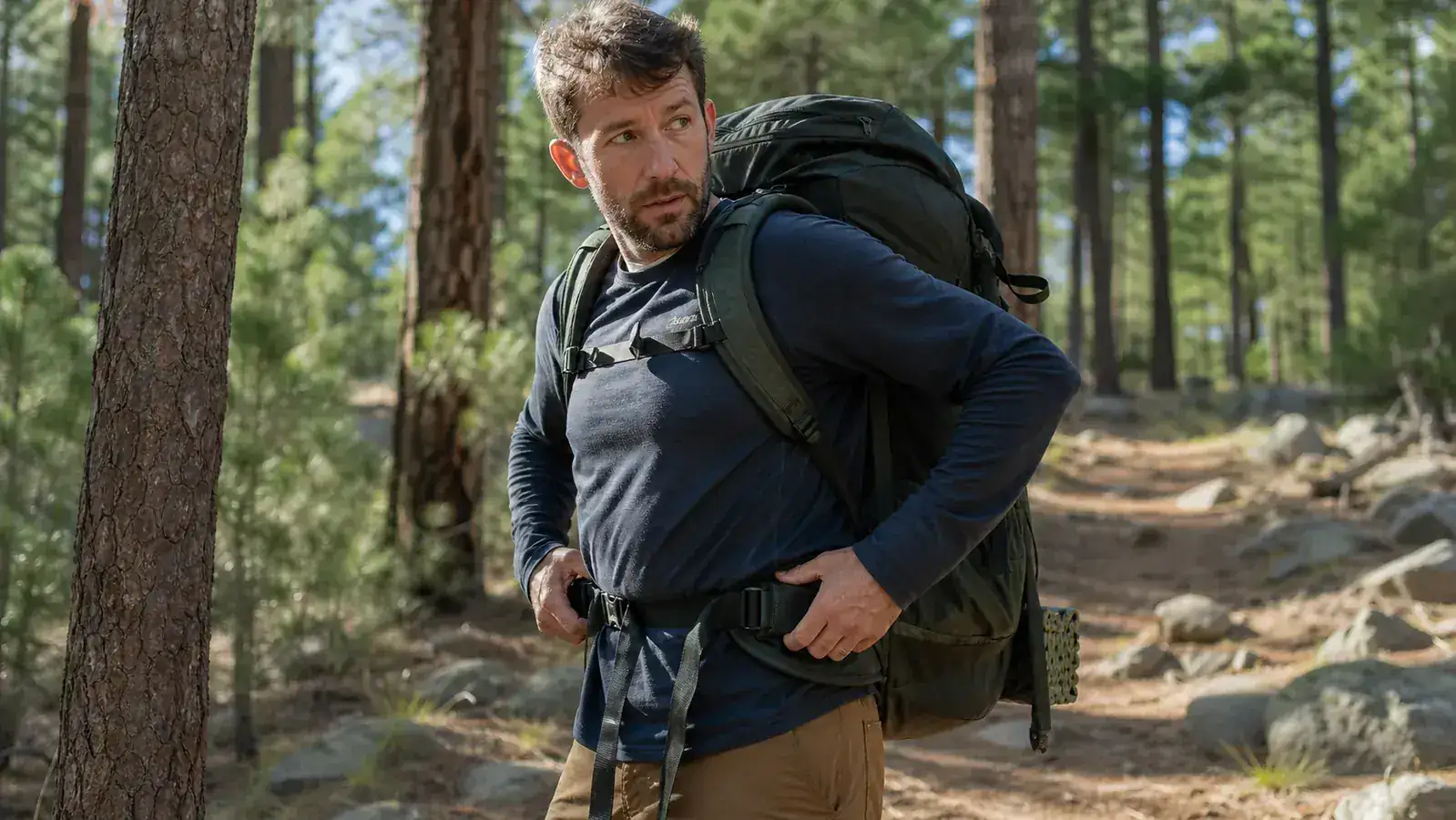 Two camping backpacks side by side on a log showing different frame and padding thickness